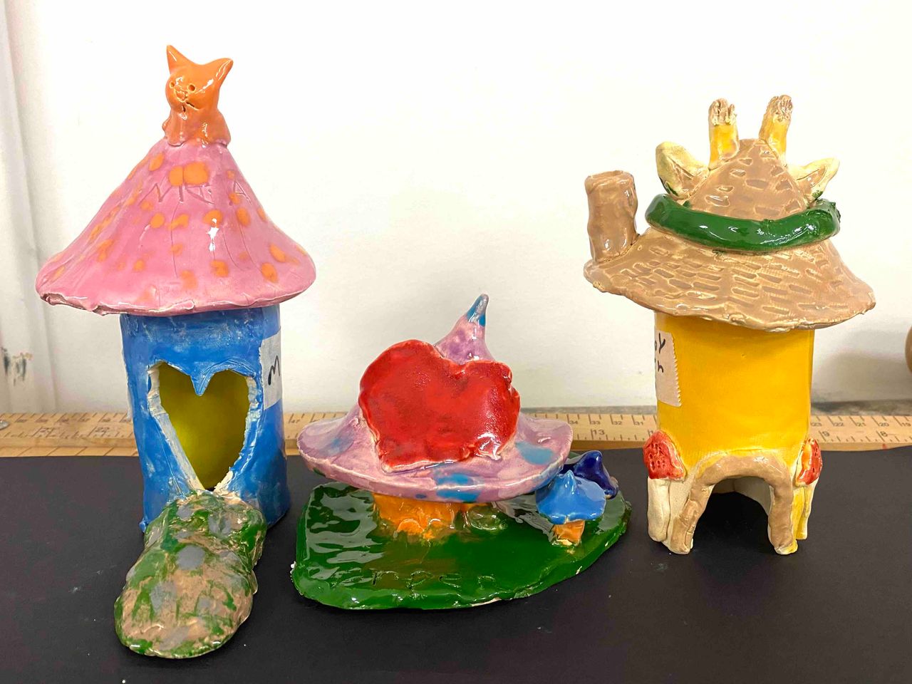 Three young artist's interpretations of gnome homes made out of clay and fired in a kiln.